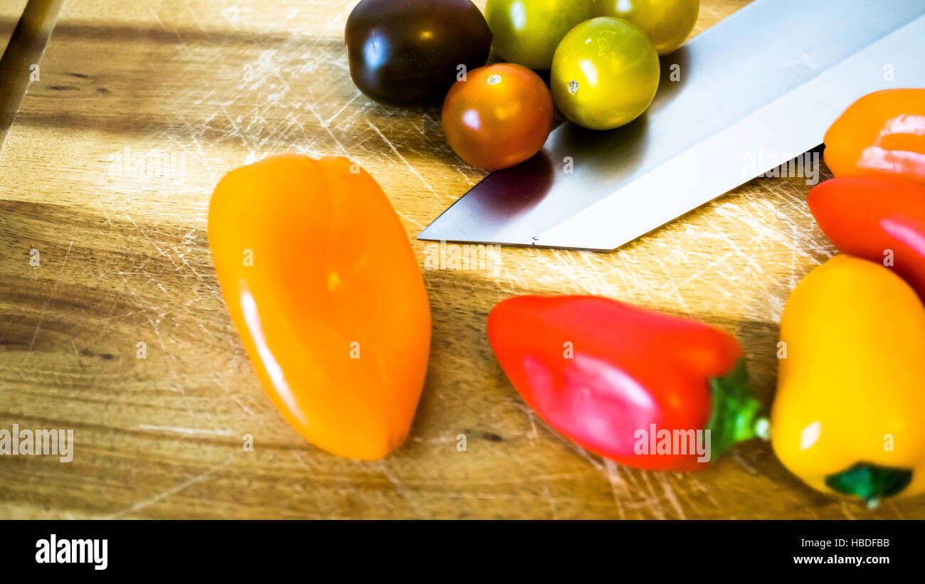 gemischte Paprika und Tomaten auf einem Schneidebrett Stockfoto