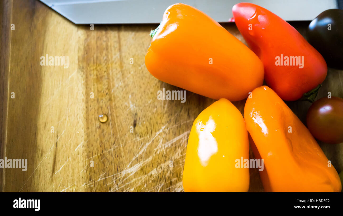 gemischte Paprika und Tomaten auf einem Schneidebrett Stockfoto