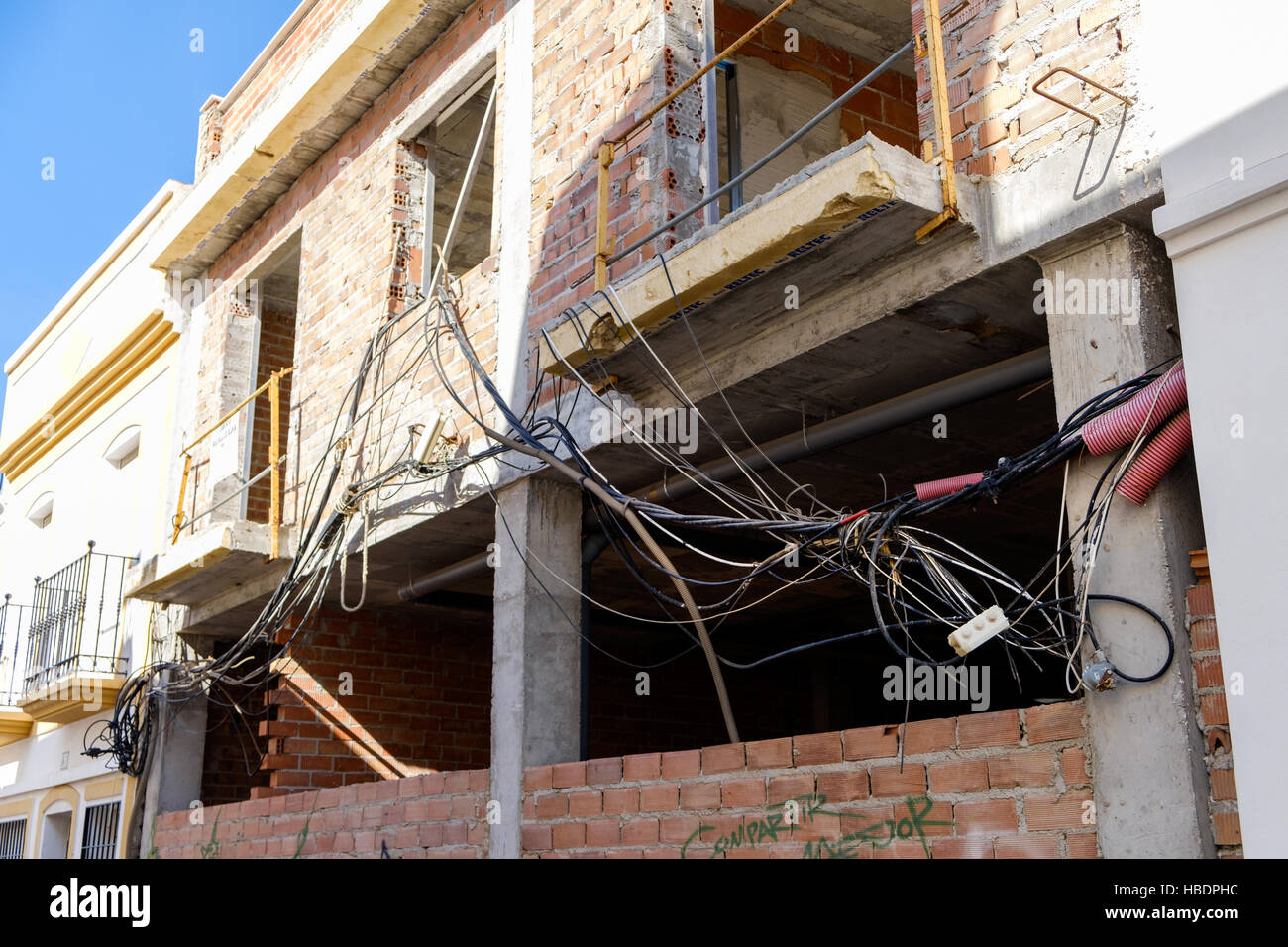 unsichere elektrische Verdrahtung verstrickt vor einem Haus in der Entwicklung Stockfoto