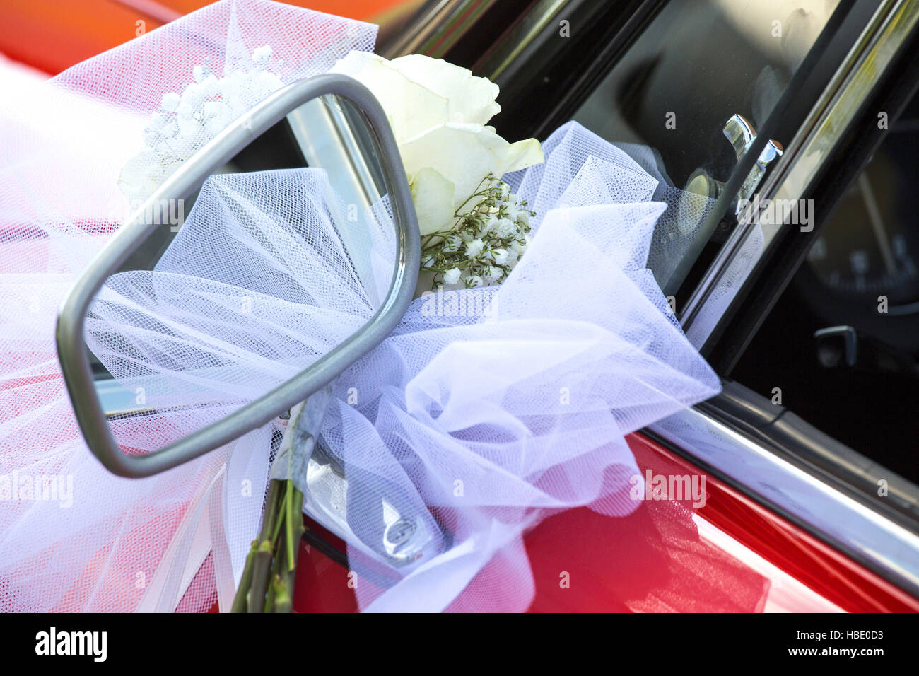 Kleinen Blumenstrauß mit weißer Schleife über ein rotes Auto. Stockfoto