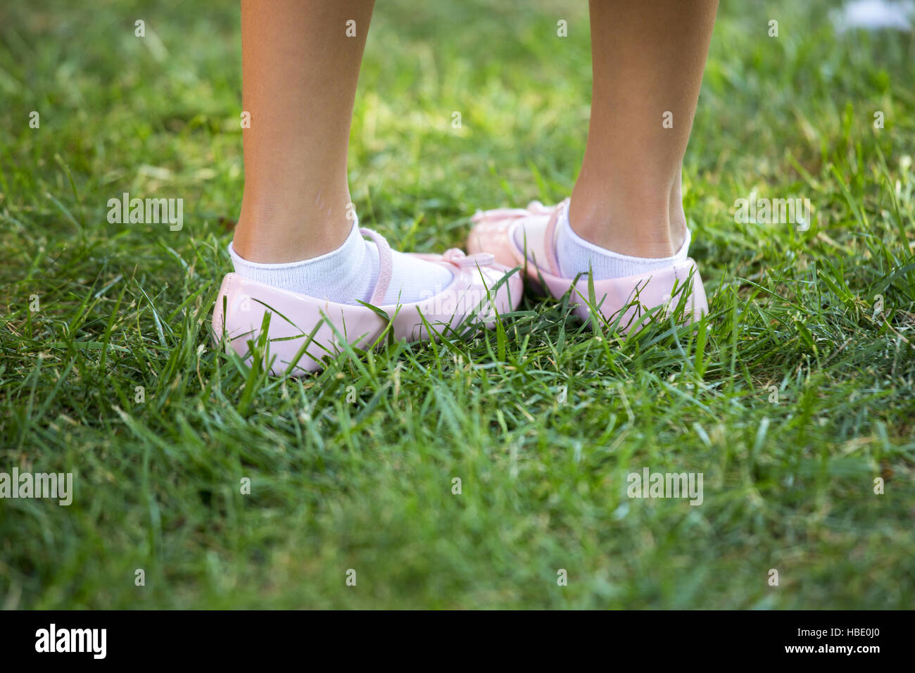 Nahaufnahme eines Kindes rosa Schuhe in einem grünen Rasen. Stockfoto