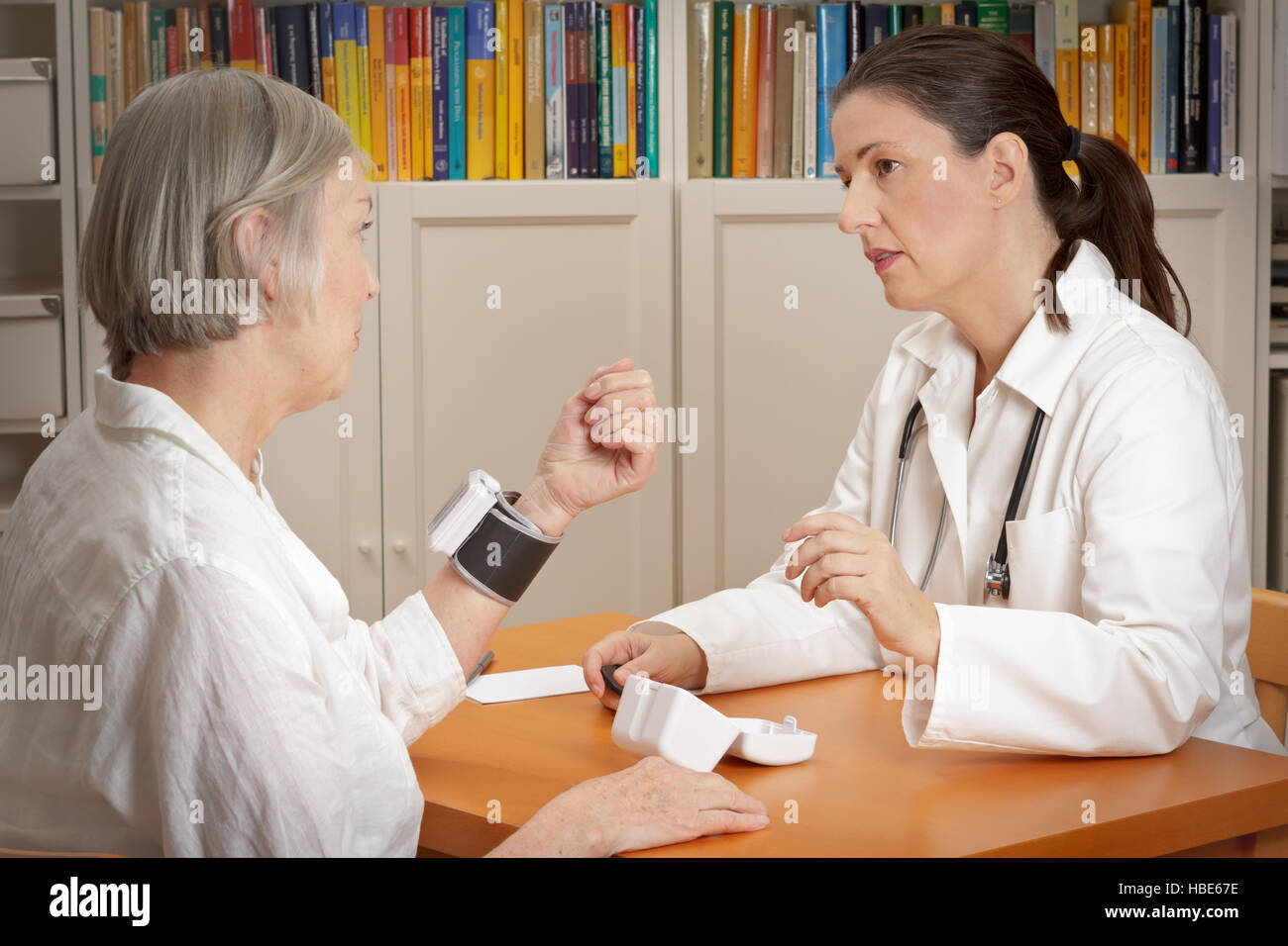 Ärztin erklärt den richtigen Gebrauch der ein Handgelenk-blutdruckmessgerät zu ihren Patienten mit hohem Blutdruck Stockfoto