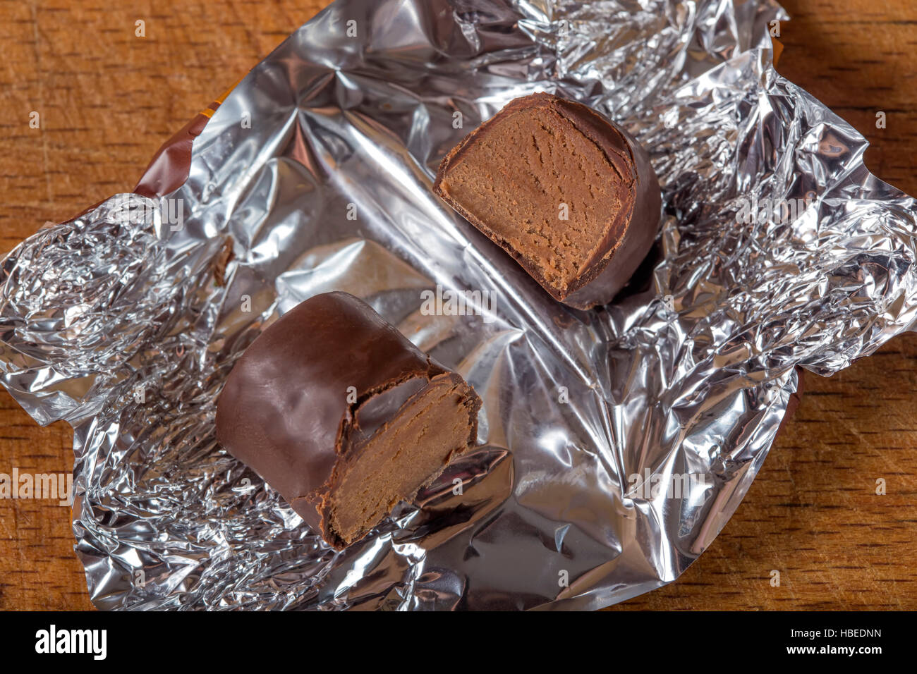 Querschnitt durch eine Praline auf Silberfolie über hölzerne Hintergrund Stockfoto