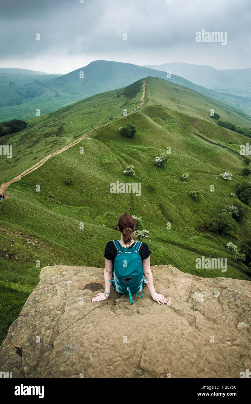 Frau sitzt auf einem Felsvorsprung, Peak District, Derbyshire, UK. Stockfoto