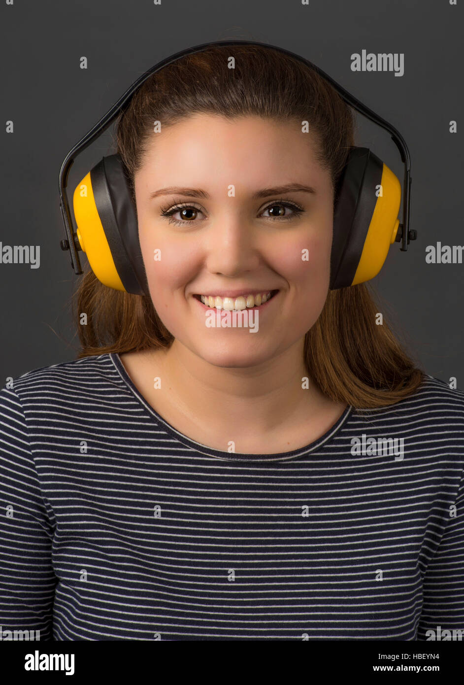 Junge Frau trägt gelbe Gehörschutz für Gehörschutz. Stockfoto
