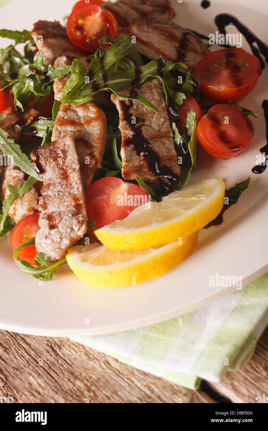 Italienischer Salat gegrilltes Rindfleisch mit Rucola und Tomaten Makro auf einem Teller. vertikale Stockfoto