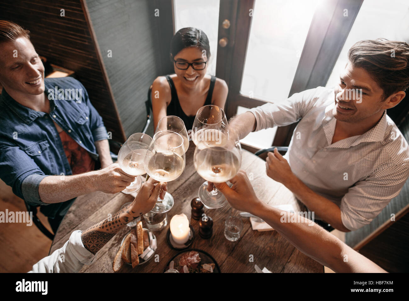 Draufsicht der jungen Männer und Frauen sitzen in einem Restaurant und Wein toasten. Gruppe von Personen, die bei einem Glas Wein im Café. Stockfoto