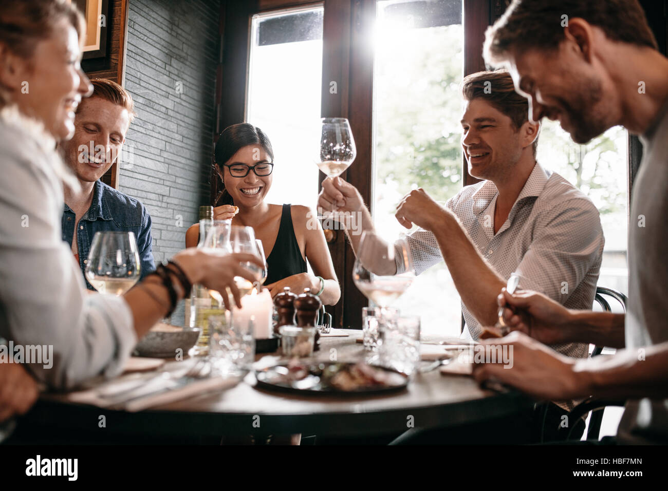 Junger Mann sein Glas Wein mit Freunden im Restaurant. Junge Menschen, Abendessen in einem Café zu genießen. Stockfoto