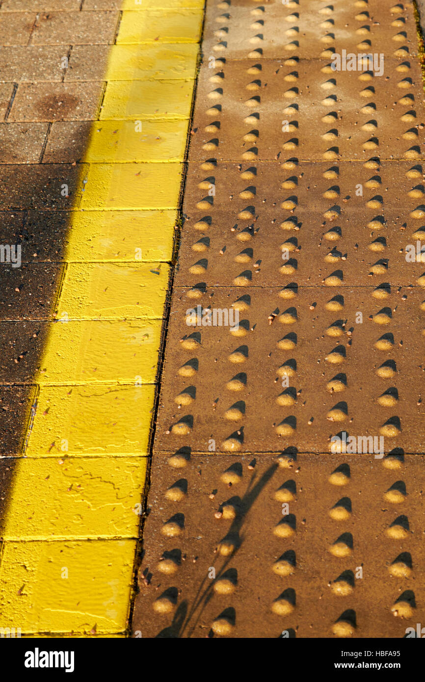 gelbe Linien und texturierte Fläche des Randes der Bahnsteig im Vereinigten Königreich Stockfoto