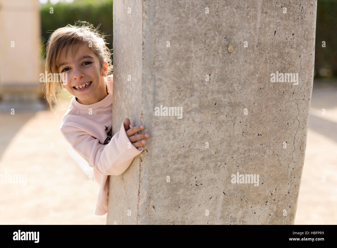 Mädchen hinter einer Steinmauer. Nehmen Sie die Hintergrundbeleuchtung horizontale. Stockfoto