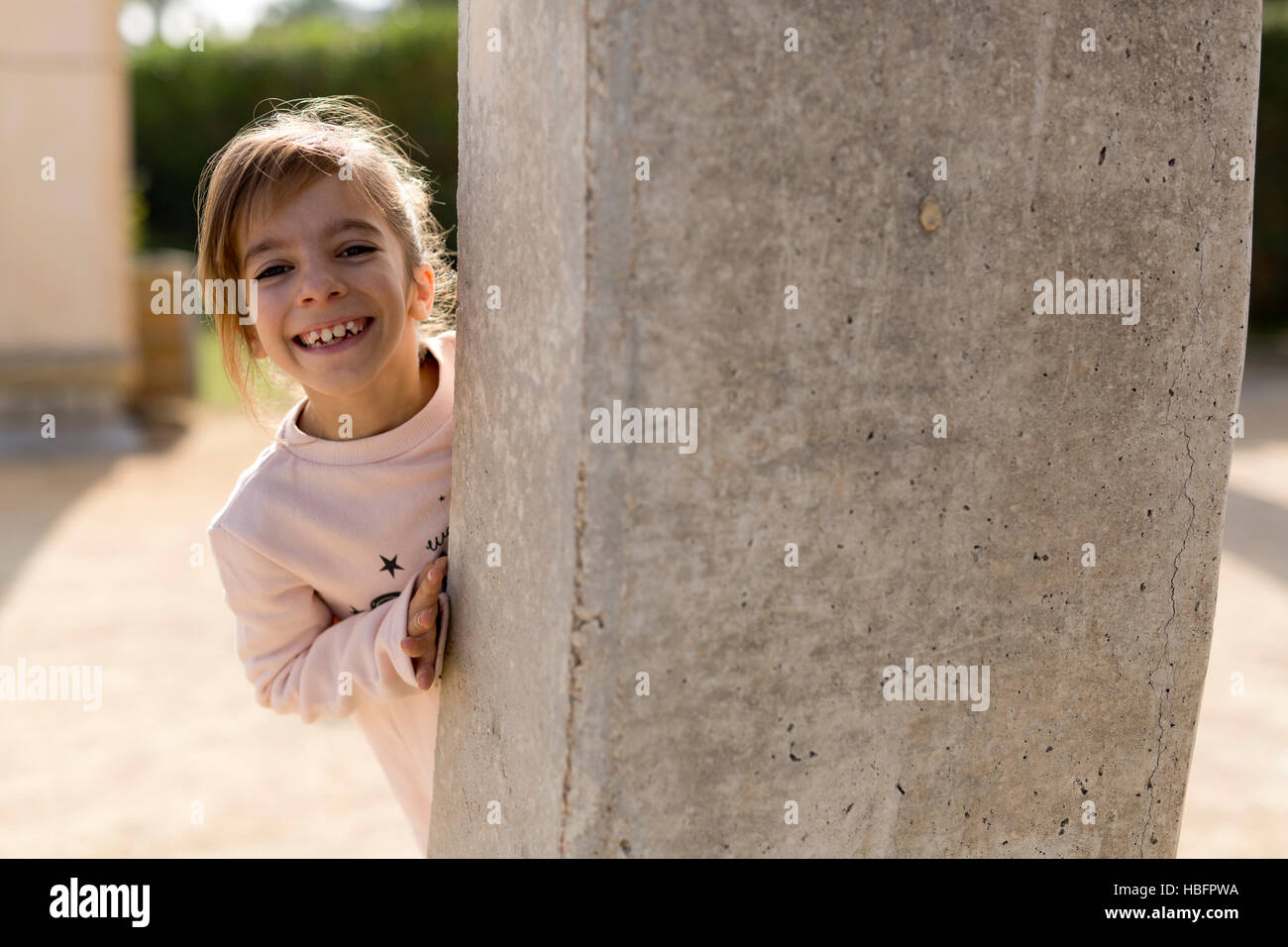 Mädchen hinter einer Steinmauer. Nehmen Sie die Hintergrundbeleuchtung horizontale. Stockfoto