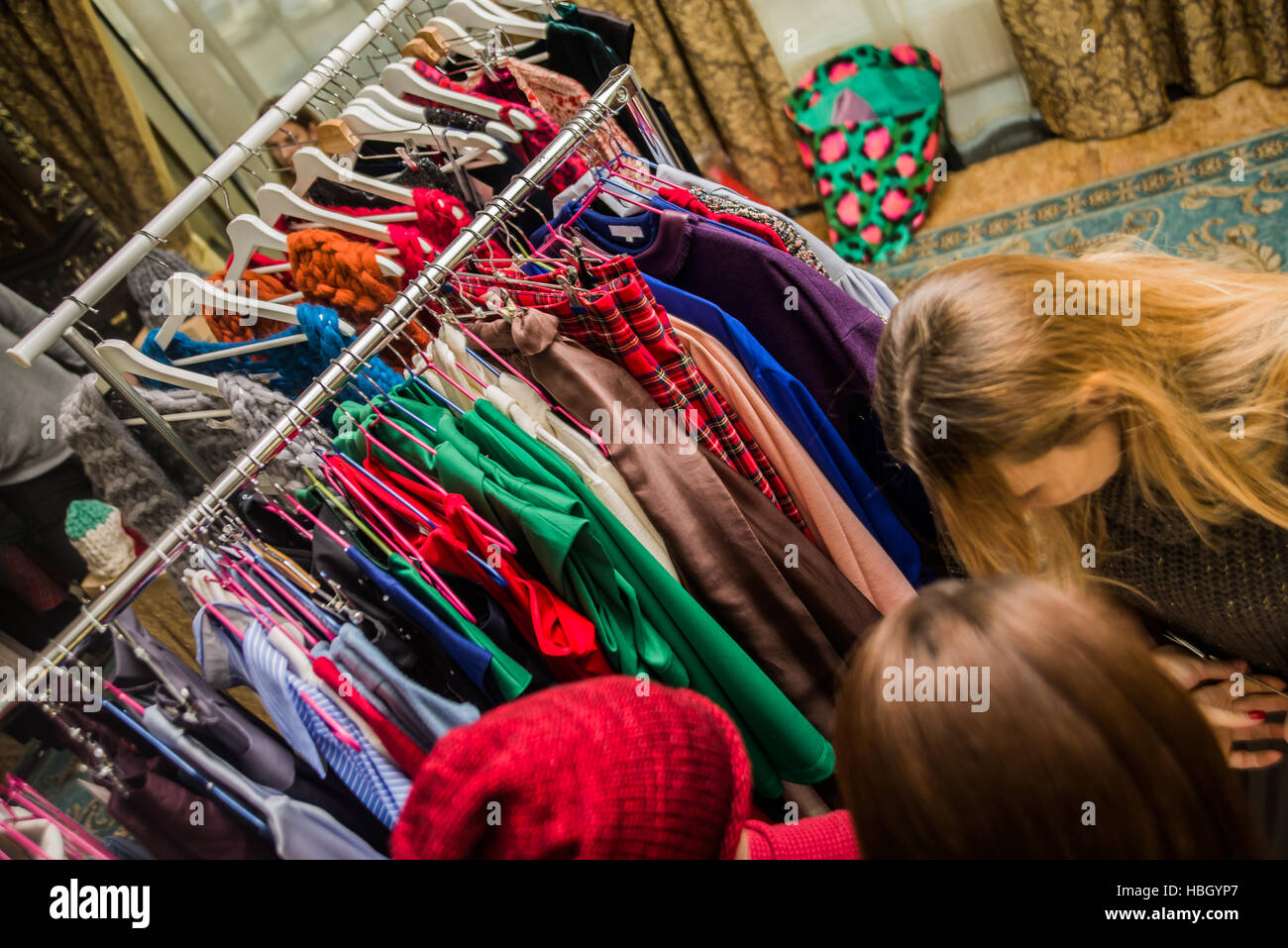 Gruppe von jungen schönen Frauen in der Fashion Mall einkaufen, neue Kleidung, Blick durch Kleiderbügel mit verschiedenen lässig bunten Kleidungsstücken auf hängen Stockfoto