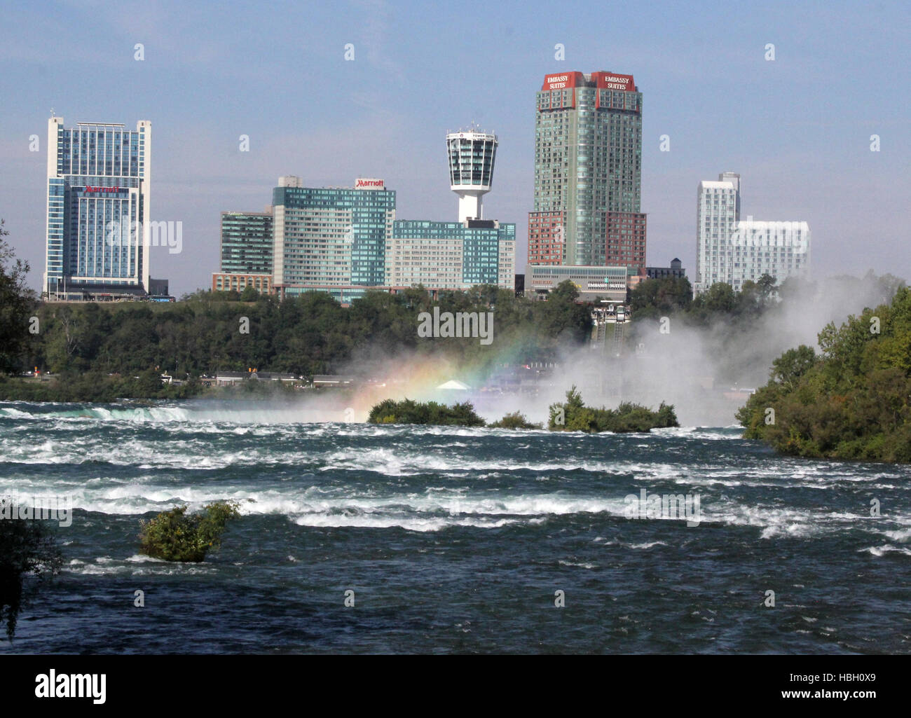 Niagara River an den Niagarafällen mit Stadtbild von Ontario im Hintergrund einschließlich Skylon Tower mit einem steigenden Regenbogen-Nebel. Stockfoto