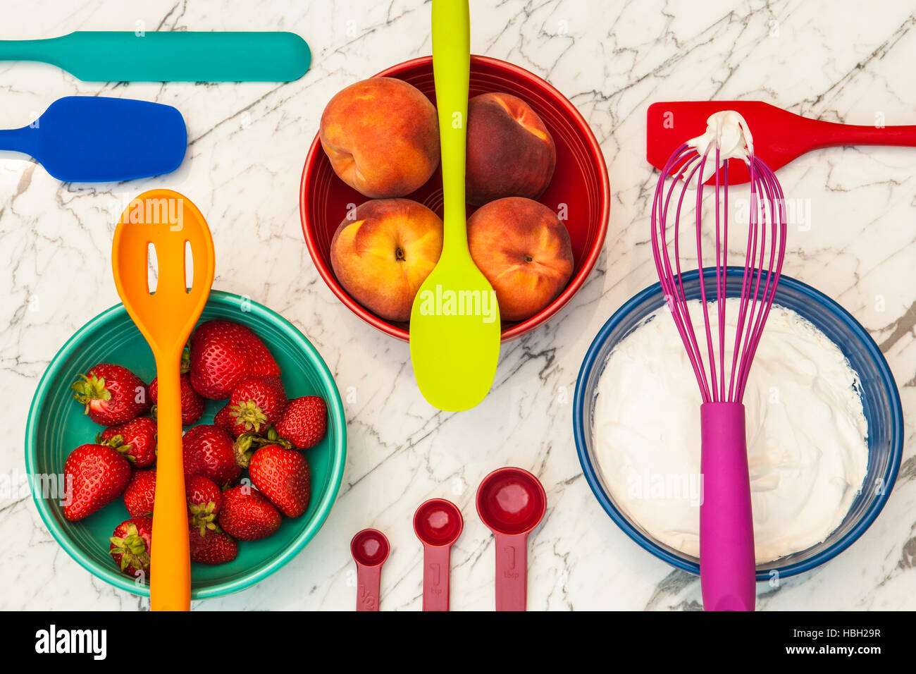 bunte Geschirr und Schalen mit Erdbeeren, Pfirsiche und Sahne Stockfoto