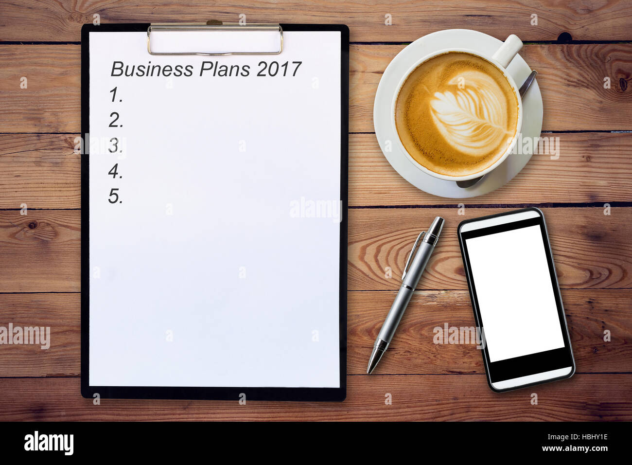 Business-Konzept - Draufsicht Zwischenablage schreiben Business Pläne 2017, Stift, Kaffeetasse und Telefon auf Holztisch. Stockfoto