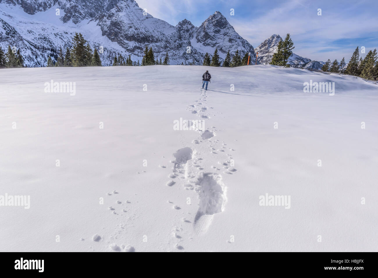 Mann zu Fuß durch Schnee auf einem Berggipfel Stockfoto