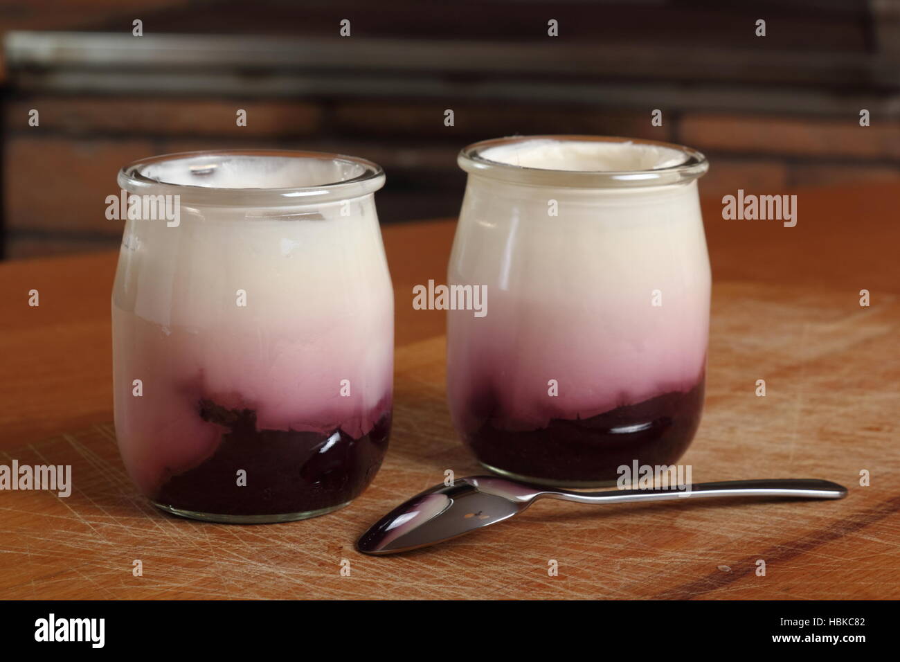 Joghurt mit Marmelade in offenen kleinen Glas mit Löffel auf Holzbrett ...