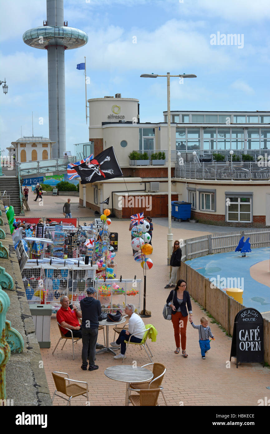 Menschen im Café und Promenade am Strand von Brighton, East Sussex, England. Mit British Airways i360 Aussichtsturm im Hintergrund Stockfoto