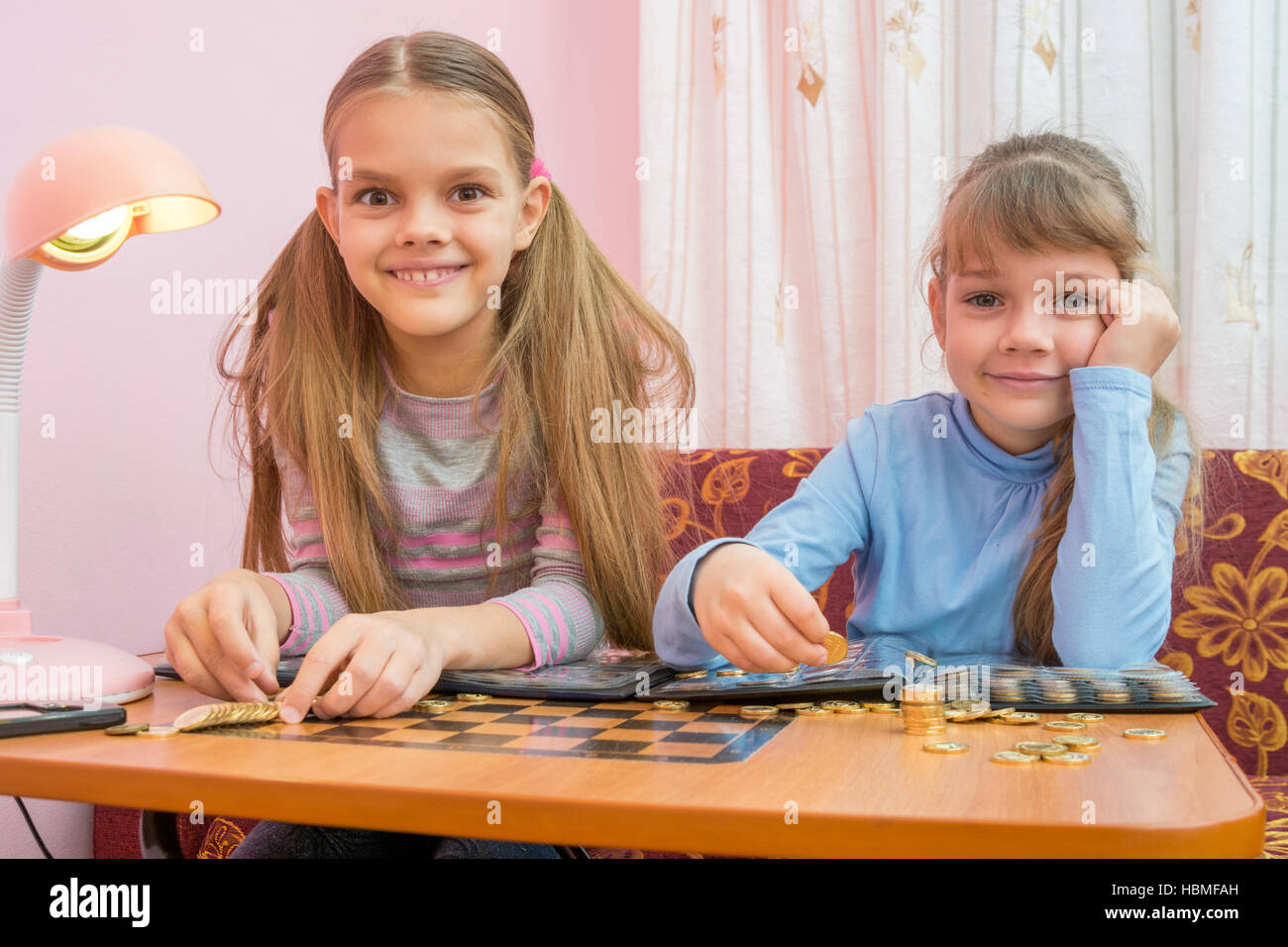 Zwei Kinder gelten als eine Sammlung von Münzen in Alben Stockfoto