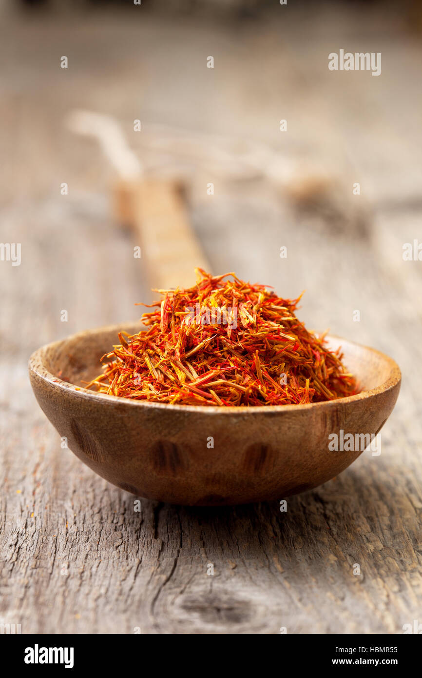 Safran in einem Holzlöffel auf dem alten hölzernen Hintergrund Stockfoto