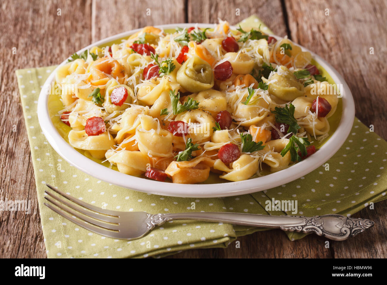 Delicious heiß bunte Tortellini mit Parmesan und geschnittene Wurst Nahaufnahme auf einer Platte. horizontale Stockfoto