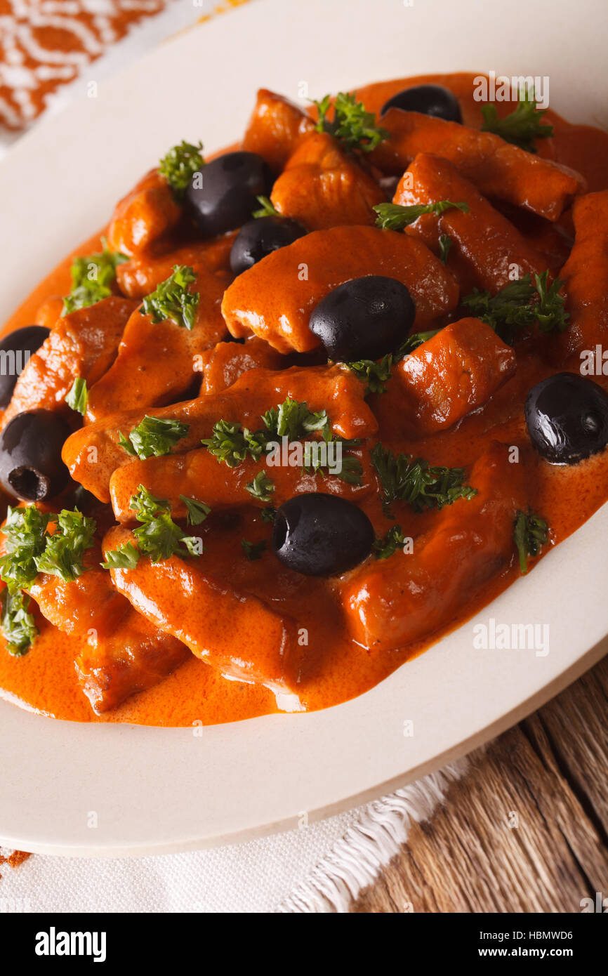 Spanisches Essen: Schweinefleisch Raxo in pikanter Sauce mit Oliven Nahaufnahme auf einer Platte. Vertikal Stockfoto