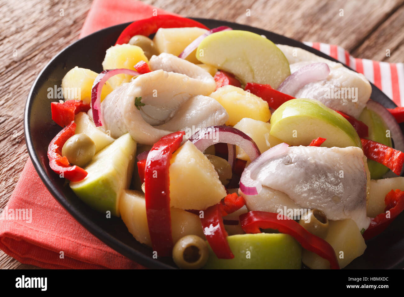Heringssalat mit Kartoffeln, grünem Apfel, rote Zwiebel, Paprika und Oliven-close-up auf einem Teller auf den Tisch. Horizontale Stockfoto