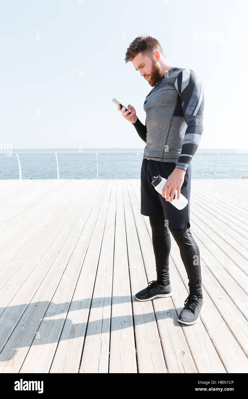 Läufer mit Wasser und Telefon. Mann steht zur Seite. Blick auf Telefon Stockfoto