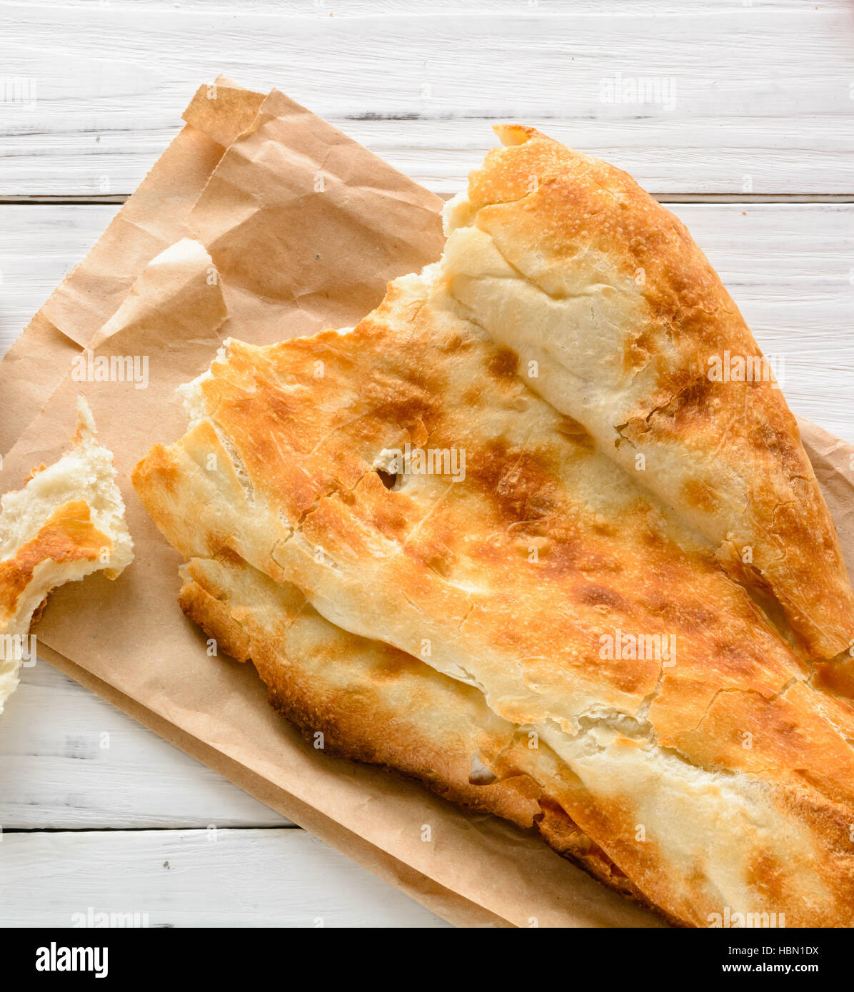 halbes Fladenbrot kaukasischen, liegend auf einem Schneidebrett gebrochen. Hellen Holz Hintergrund. Stockfoto