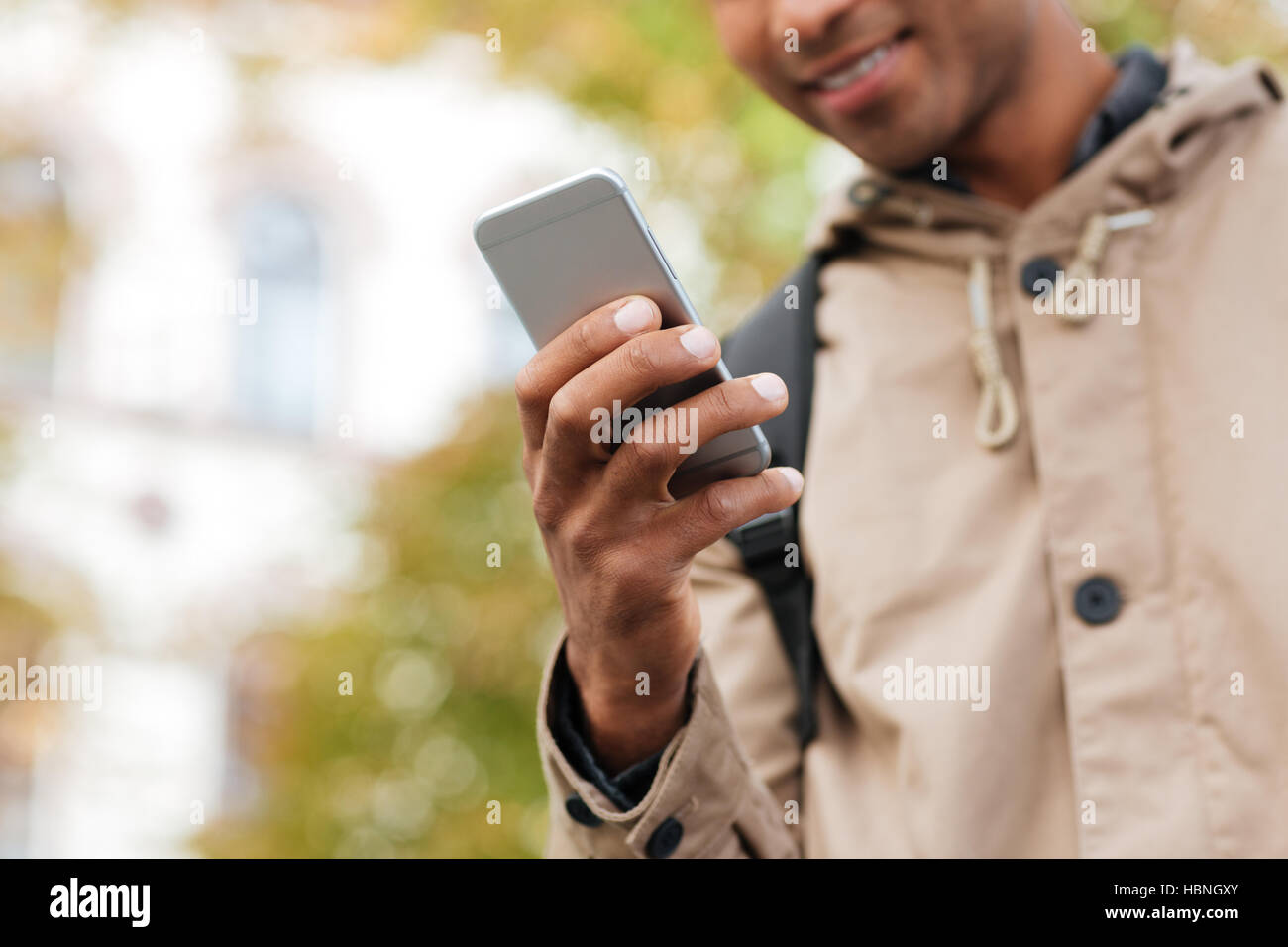 Foto von dunklen enthäuteten Jüngling mit seinem Handy auf der Straße abgeschnitten. Stockfoto