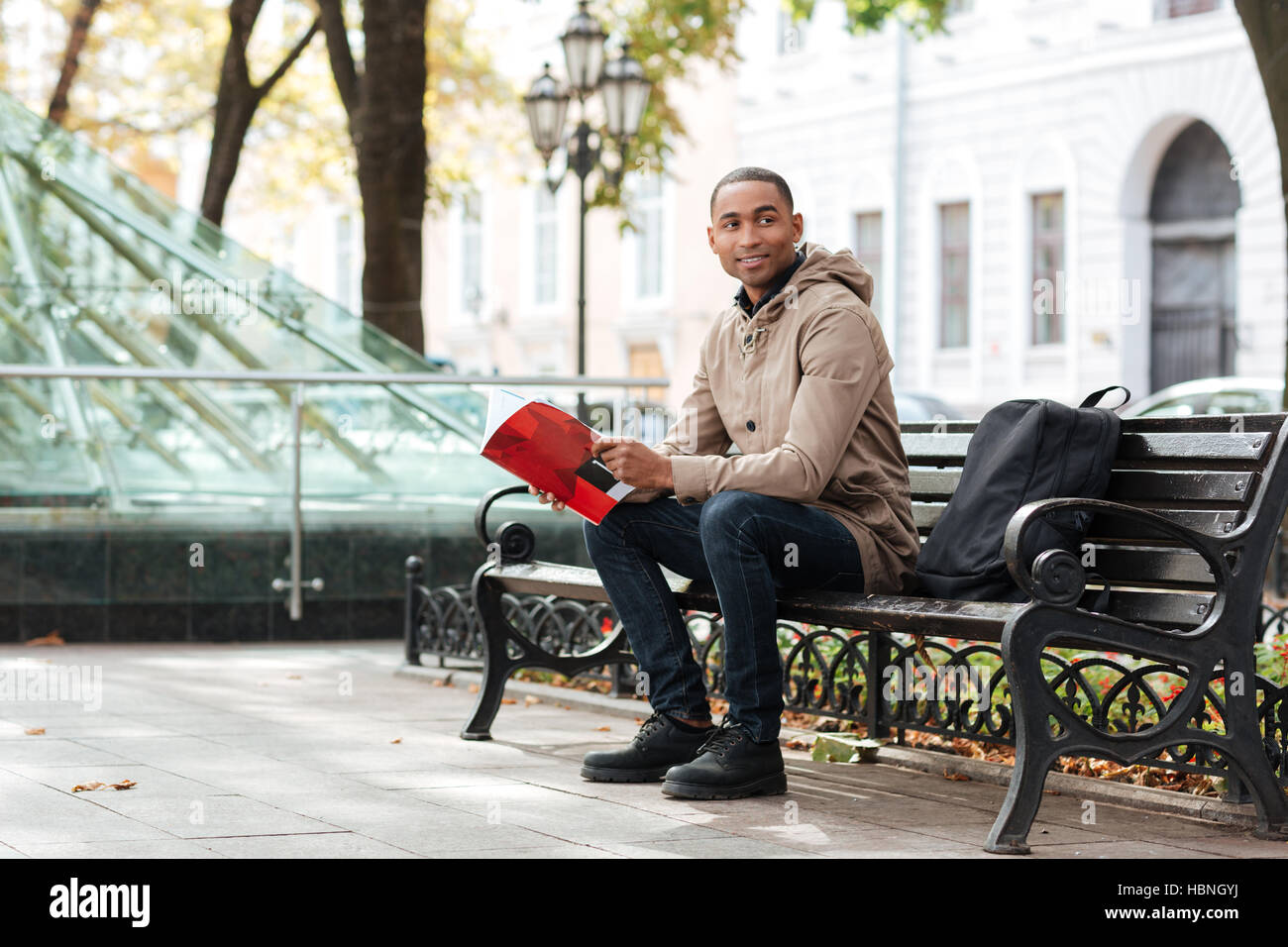 Bild der jungen afrikanischen glücklicher Mann Blick beiseite, beim Lesen eines Buches. Stockfoto