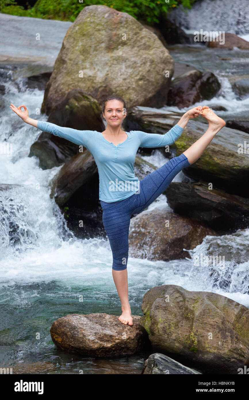 Frau tut Ashtanga Vinyasa Yoga Asana im Freien am Wasserfall Stockfoto