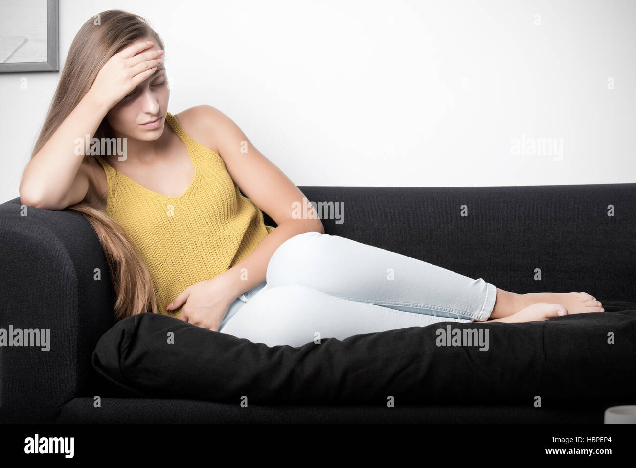 Frau vor Schmerz auf einer Couch Stockfoto