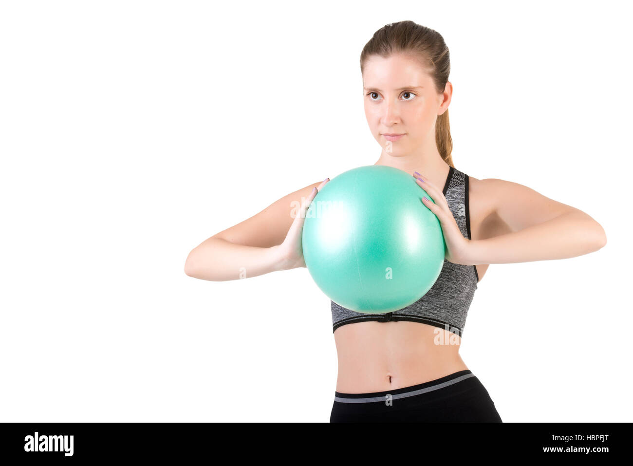 Passen Sie Frau stehend mit einem Pilates Ball Stockfoto