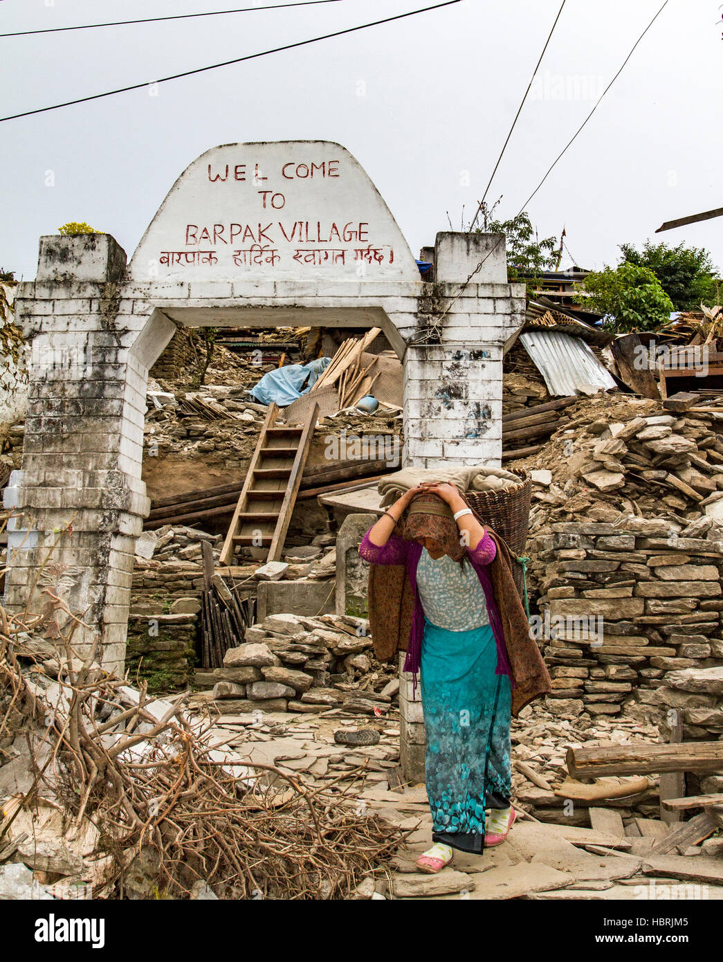 Nach einem Erdbeben von 7,9 Millionen Menschen in Nepal geht eine Frau durch die verwüsteten Ruinen des Dorfes Barpak im Gorkha District in Nepal. Stockfoto