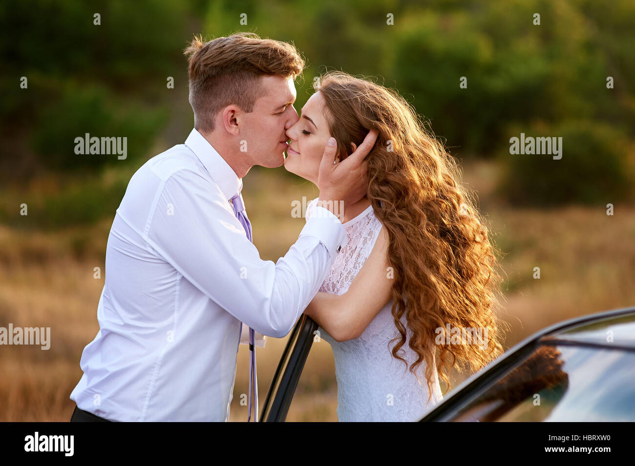 Braut und Bräutigam küssen in der Nähe von Auto auf Hochzeit gehen Stockfoto