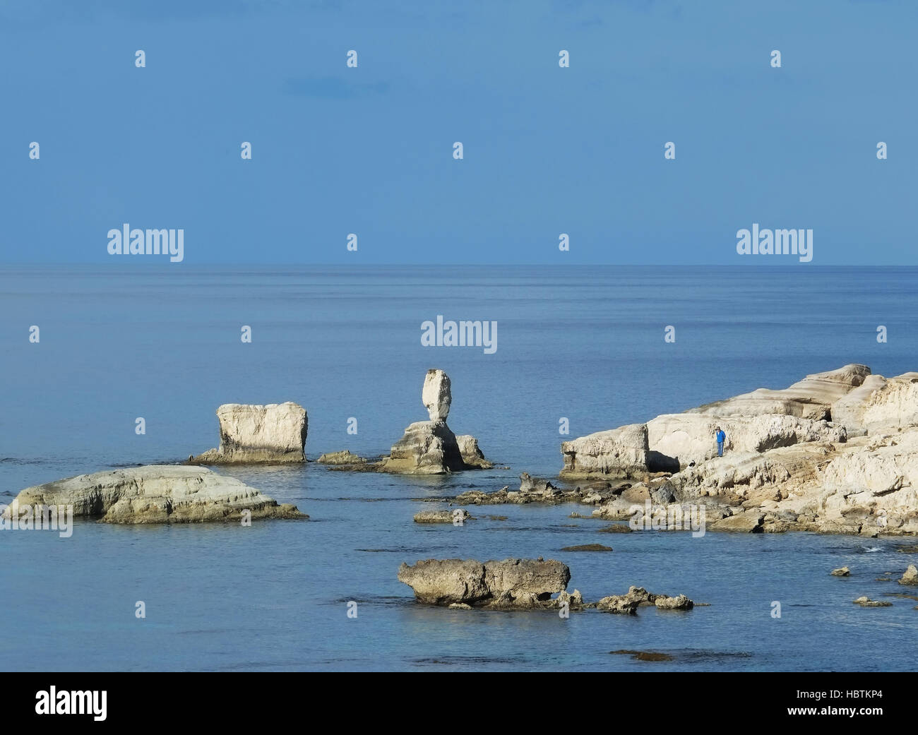 Ein Mann steht auf den Felsen am Meer Höhlen in der Nähe von Peyia im Bezirk Paphos. Stockfoto