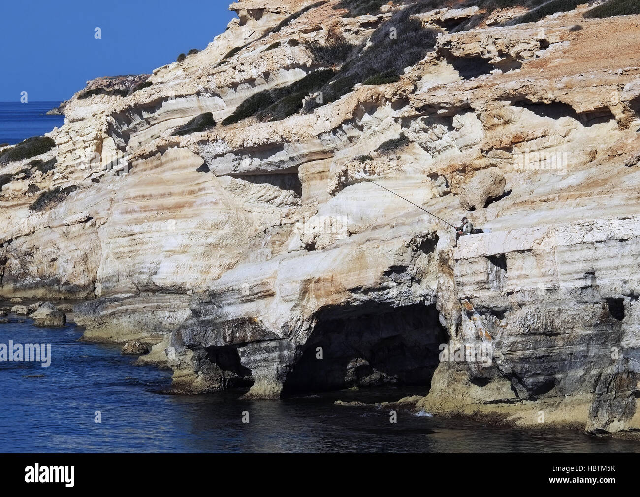 Ein Mann Fische aus den Felsen am Meer Höhlen in der Nähe von Peyia im Bezirk Paphos. Stockfoto