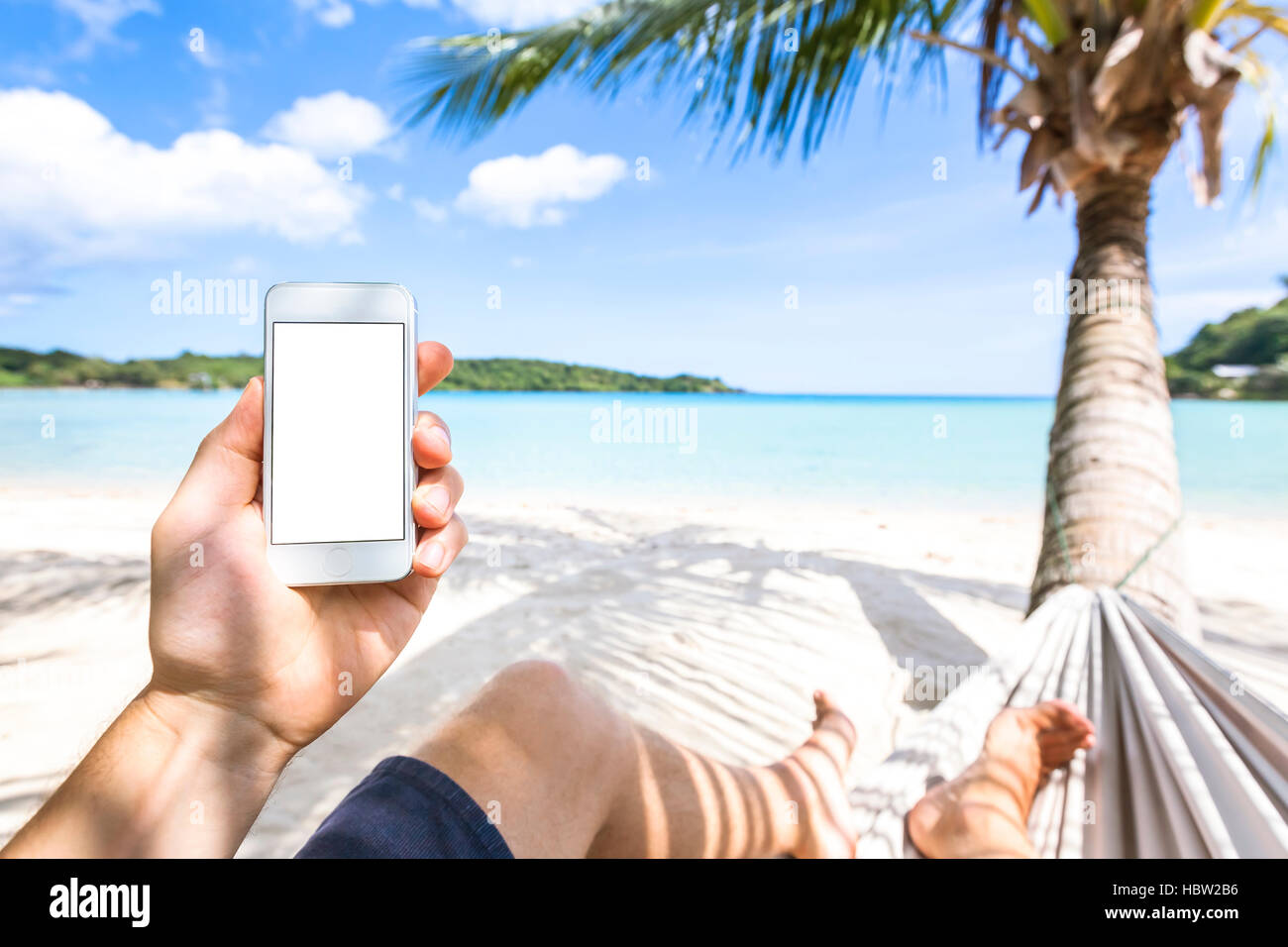 Verwendung von Smartphone auf ein tropisches Paradiesstrand sitzen in Hängematte, Handy und Technik während der Ferien am Meer Stockfoto