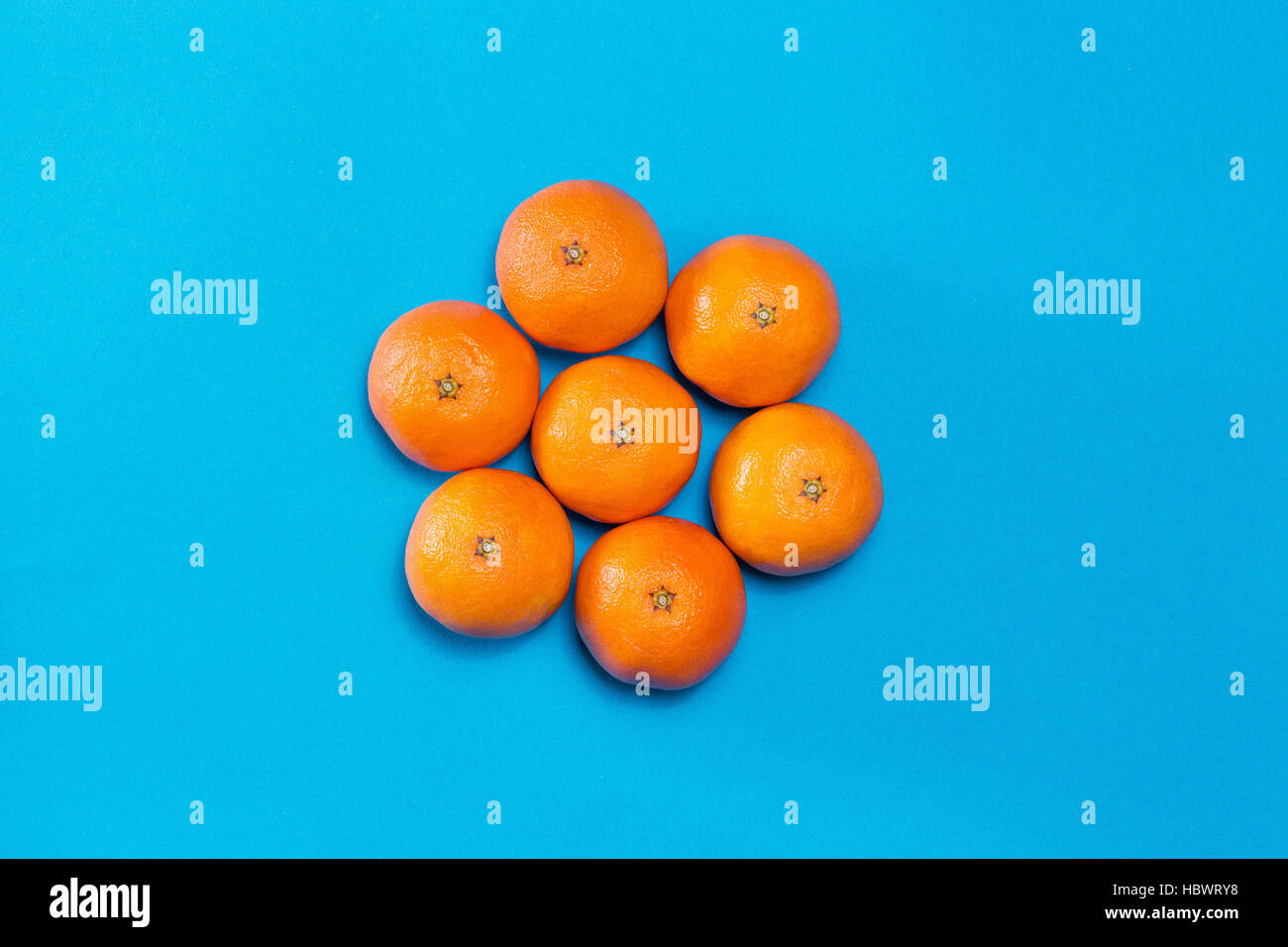 Sechs bunte frische orangene Mandarinen angelegt auf blaue Tabelle mit textfreiraum von oben gesehen. Konzept-Sonne am Himmel. Stockfoto