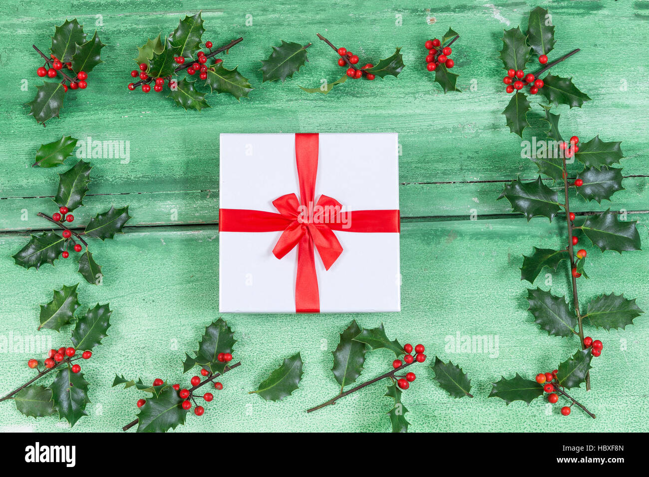Schöne Cristmas Geschenke, die ich Mitte der Stechpalme auf alten grün lackiert Holz Hintergrund geknackt Stockfoto