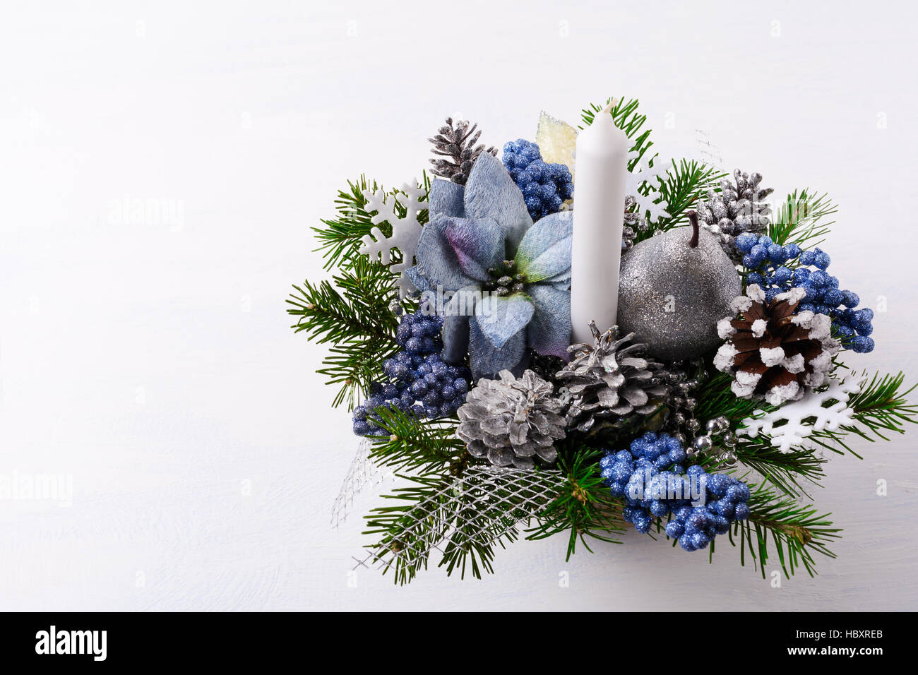 Weihnachten Hintergrund mit Kerze und blaue Seide Weihnachtssternen. Künstliche Blume Weihnachtsarrangement mit Tannenzapfen und Tannenzweigen. Weihnachtstisch Stockfoto