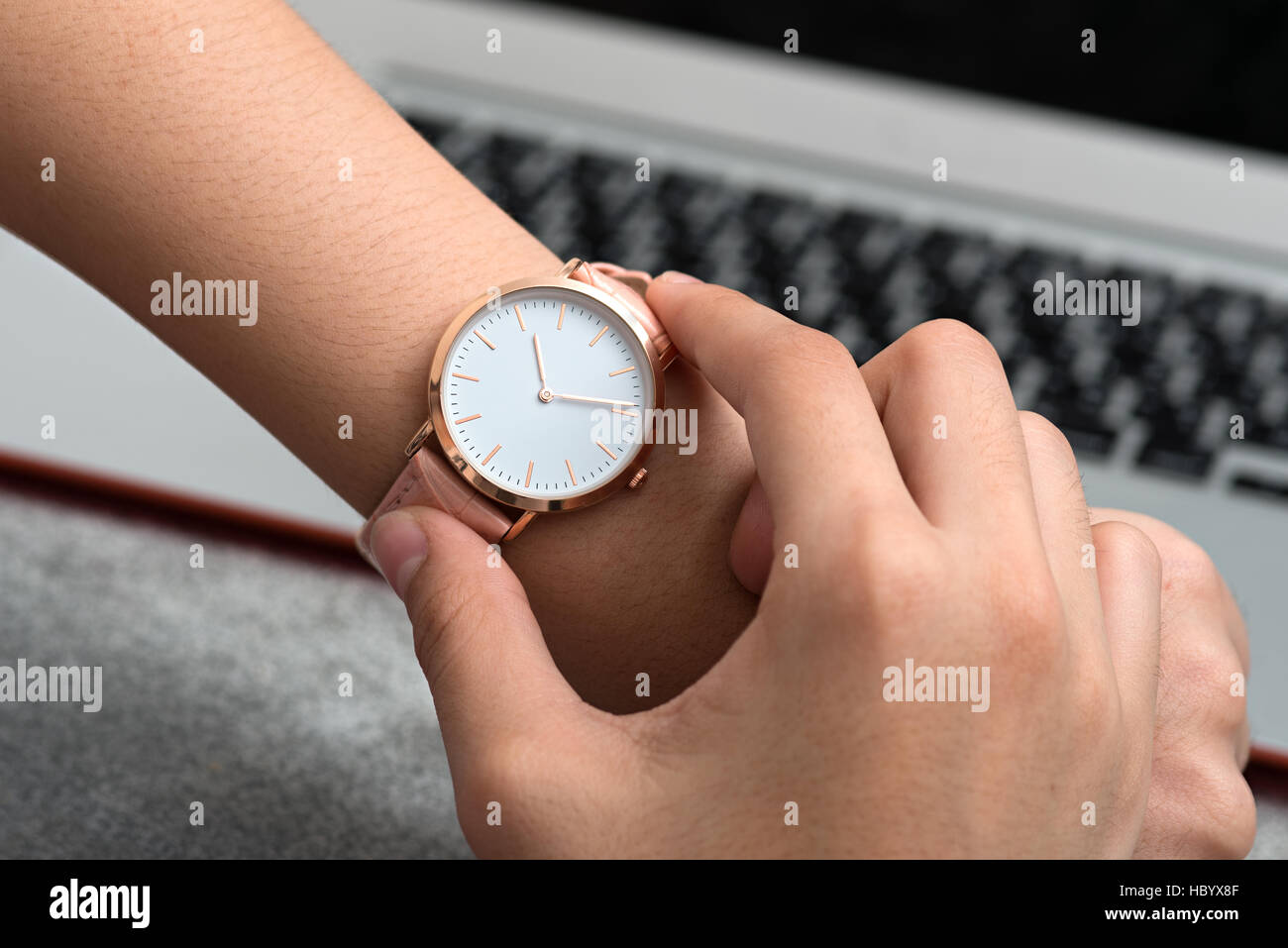 Mädchens Hand mit Armbanduhr vor Schreibtisch mit Notebook Stockfoto