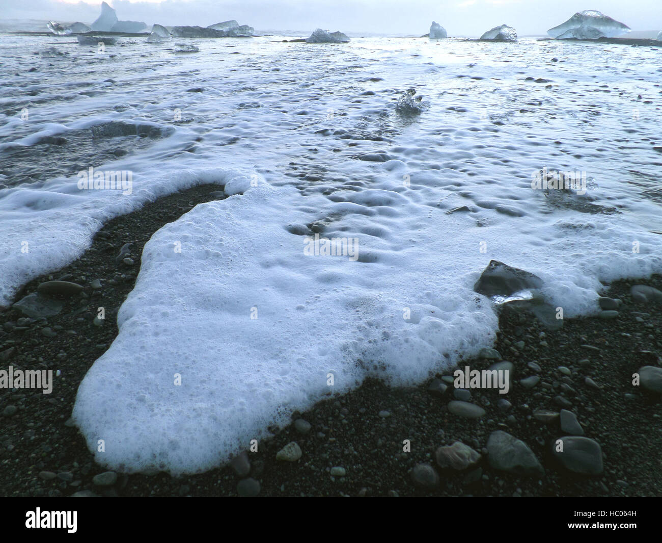 Wave-Bubbles und schmelzende Eisberge auf dem schwarzen Sand Strand von Island Stockfoto