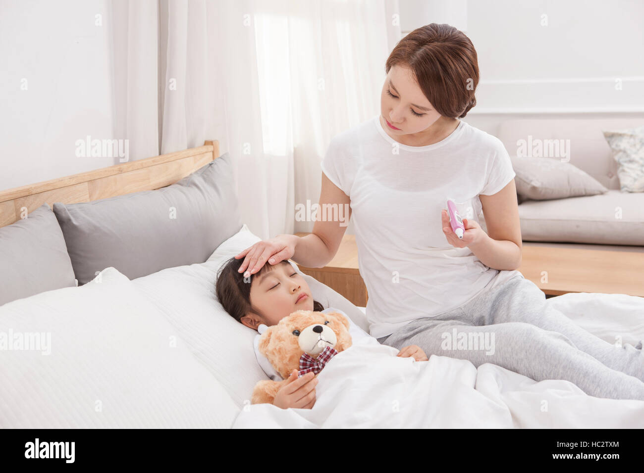 Liebevolle Mutter kümmert sich um ihre Tochter schlafen mit Teddybär Stockfoto