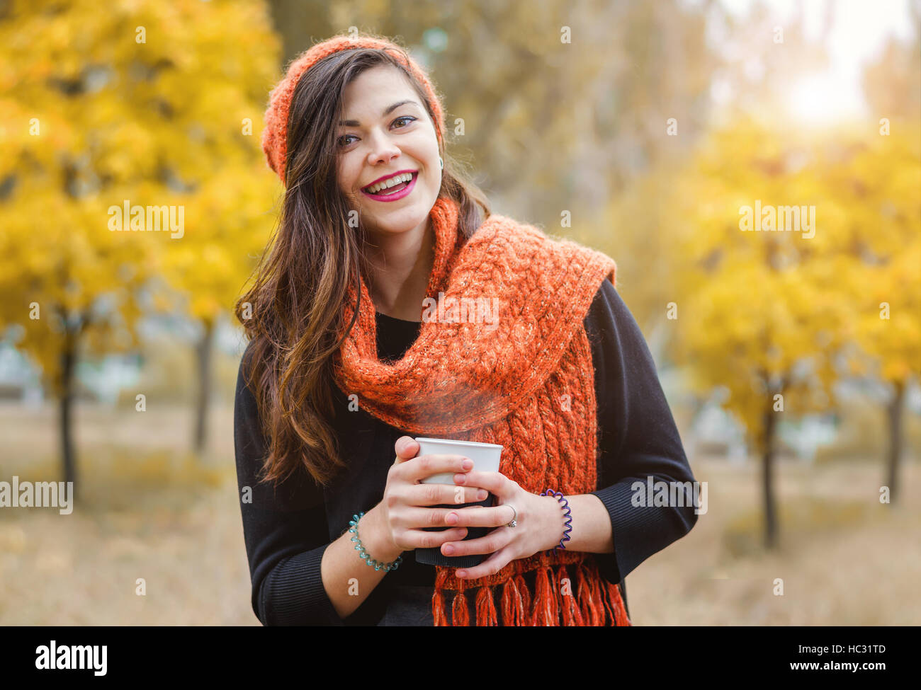 Lachende Mädchen mit einer Tasse Kaffee (Tee) für einen Spaziergang im Park im Freien. Herbstwetter. Stockfoto