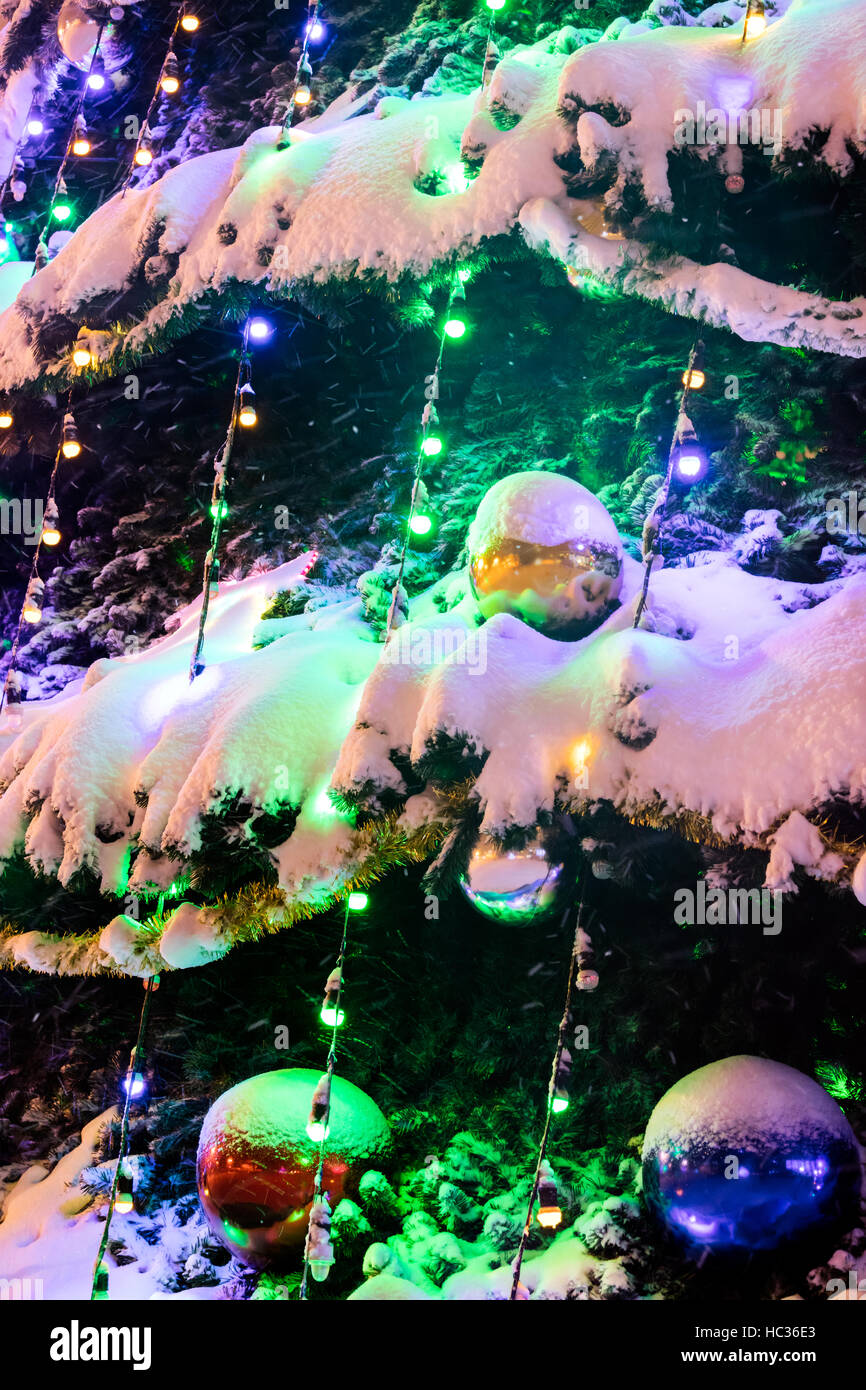 verschiedenen Weihnachtskugeln auf Tanne unter Schnee und hellen Weihnachtsschmuck Stockfoto