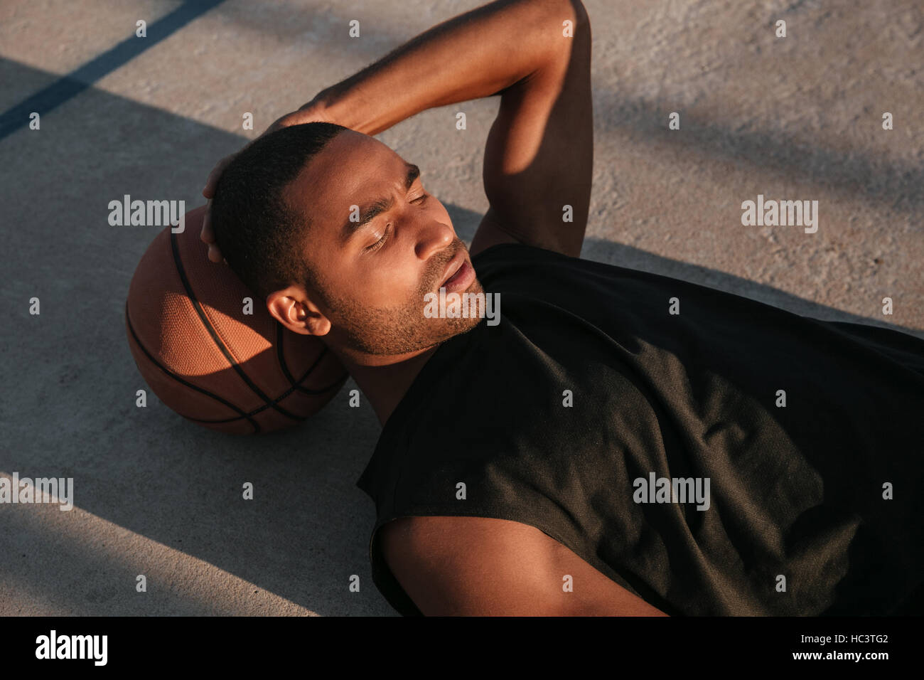 Closr Porträt eines Mannes müde Afro amerikanische Sportarten ruht auf einem Basketball auf dem Spielplatz Stockfoto