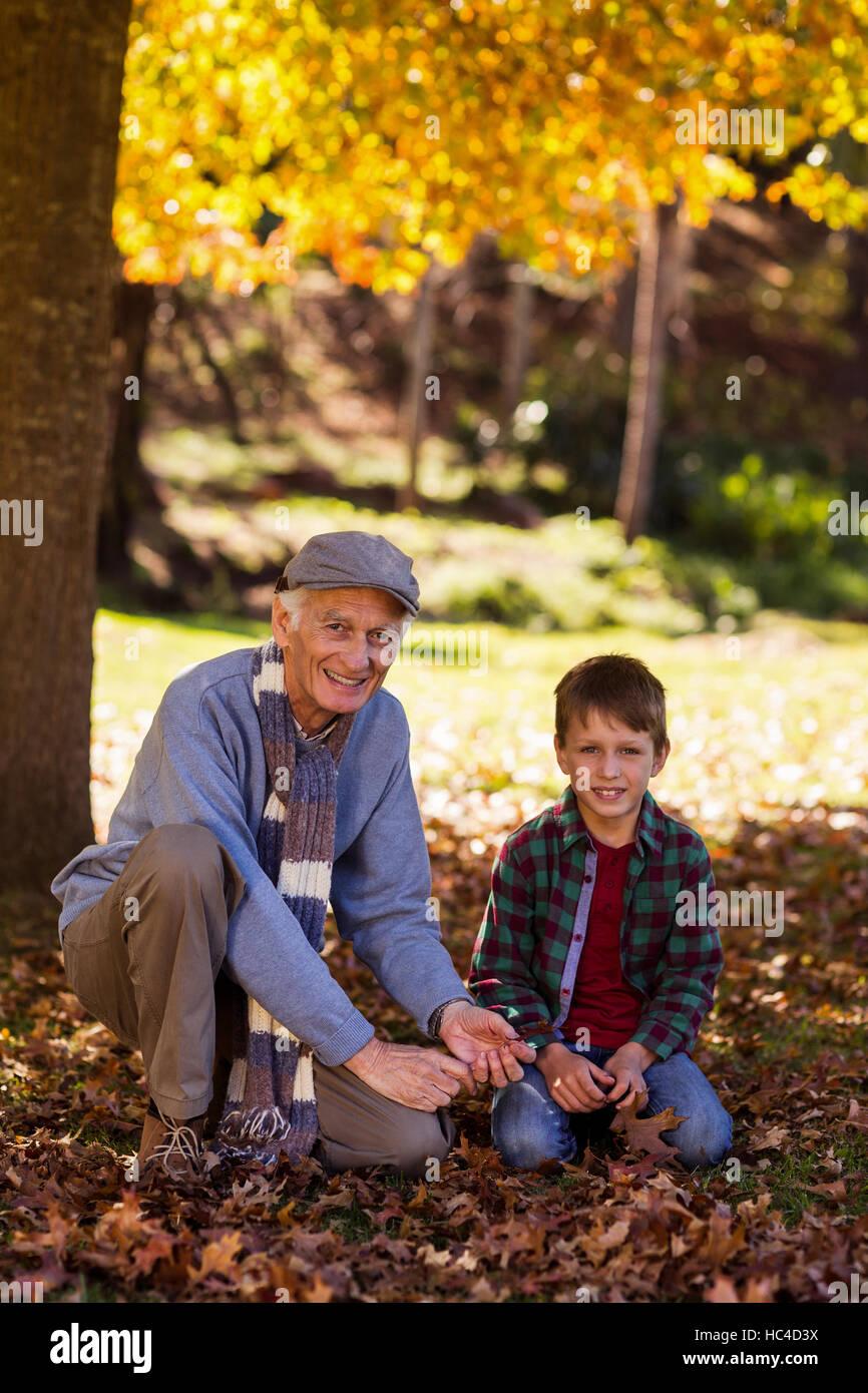 Porträt von Großvater und Enkel spielen mit Herbstlaub Stockfoto