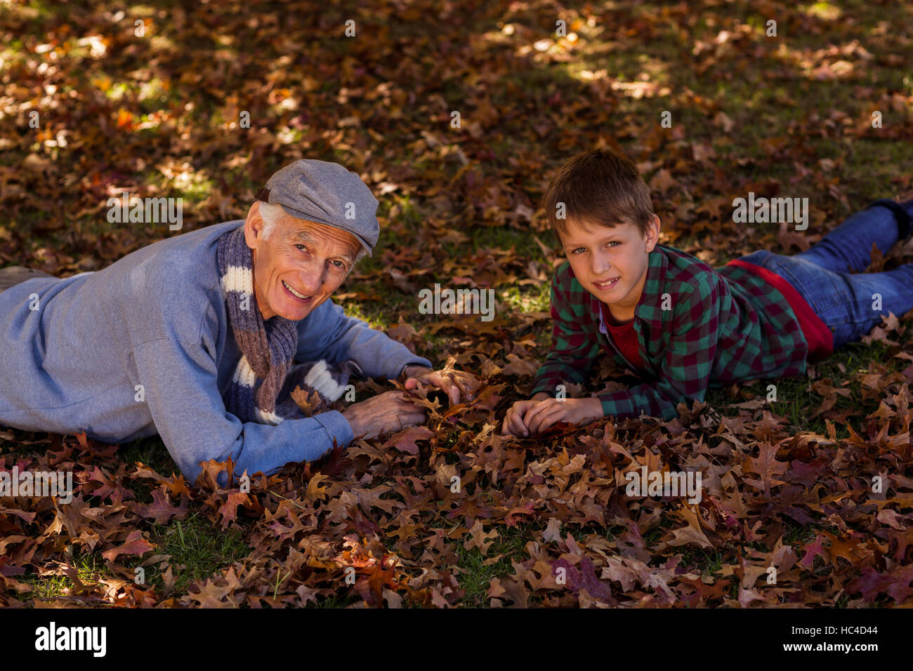 Großvater und Enkel auf Herbstlaub liegend Stockfoto